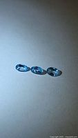 Three oval cut blue gemstones on neutral background