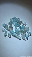 Group of light blue zircon rough crystals displayed on white background