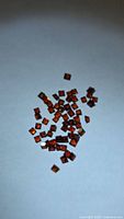 pile of small square orange-red garnet stones on white background