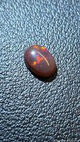 Front view of oval chocolate opal showing burgundy body and multicolor play-of-color