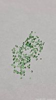 Group of tiny green tsavorite garnet stones on white background