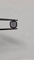 Spinel held in tweezers side view