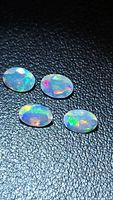 Four oval faceted opals displayed on black textured surface