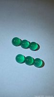 Six round vivid green cabochon stones on light background