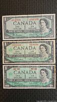 Fronts of three 1967 Canadian $1 bills showing serials and portrait