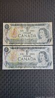 Fronts of both 1973 Canadian $1 notes showing serial numbers and portrait