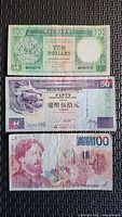 Obverse sides of three banknotes stacked: HK$10, HK$50, BEF100