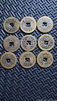 Front view of nine brass Chinese coins showing inscriptions