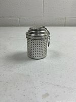 Front view of perforated aluminum infuser showing removable lid