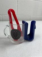 Glass mug with Oreo logo, red tongs, blue rack