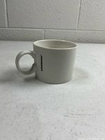 Left profile of white Starbucks mug showing handle and logo