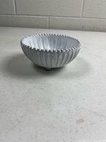 Side view showing beaded rim, fluted sides, and feet