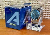 Watch on display stand beside branded box showing overall appearance