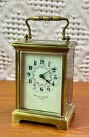 Front view of brass carriage clock showing dial and handle