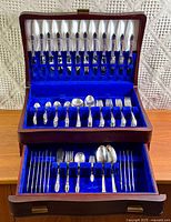 Open chest showing two tiers of flatware pieces in holders