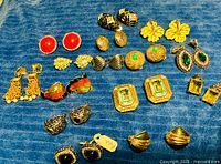 All earrings laid out on blue fabric, full lot overview