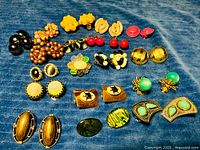 Full layout of 15 pairs clip-on earrings on blue fabric