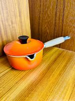 Saucepan with lid, side view showing flame enamel, wood handle and pour spout