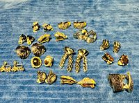 Lot overview of 17 pairs of vintage gold-tone and silver-tone clip-on earrings arranged on blue cloth
