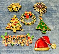Seven vintage holiday and floral brooches on fabric background