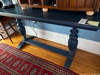 Full view of blue painted console table against wall showing top, base, and surrounding area
