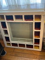 Full view of square stained glass window panel in white frame