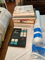 Stack of seven instructional books and two sealed sumi-e paper rolls