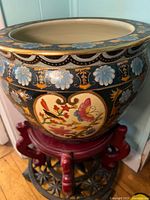 Overall view of fishbowl planter on red carved stand showing exterior motifs and scale