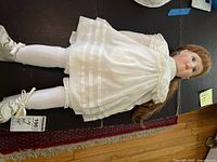 Full view of 28" porcelain doll in white dress, tights and boots