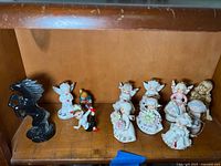 Shelf view showing black horse, small angel, Occupied Japan children figurine and line of birthday angels