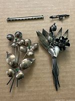 All four sterling silver pins laid out: two large floral brooches, bar pin, small stem pin