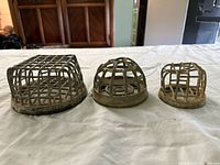 Front view of all three brass drain strainers showing cage tops and relative sizes