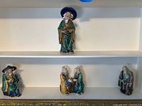 All five ceramic scholar figurines on shelves