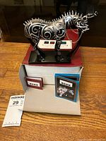 Figurine on base atop open box with pamphlets visible