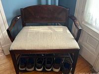 Front view of wooden bench with upholstered seat and lower shoe rack