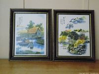Both framed Asian landscape paintings side by side showing artwork and frames