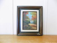 Front view of framed landscape artwork showing waterfall scene and frame details