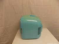 Left side view showing aqua cabinet, vent slots, scuffs