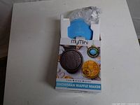 Open box showing blue waffle maker in packaging