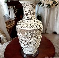 Full view of carved cinnabar vase on stand showing floral relief and borders