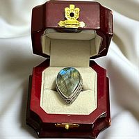 Ring displayed in wooden presentation box showing stone and bezel