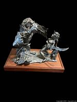 Three-quarter view of full sculpture showing lion creature and female figure on wood base