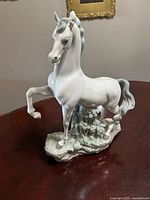 Front view of signed Lladro porcelain horse figurine on leafy base