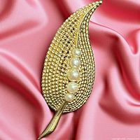 Front view showing gold-tone leaf shape with four faux pearls