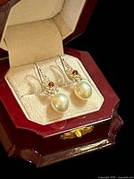 Earrings in open red wood box showing front details