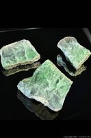 Three green fluorite slabs displayed on black surface