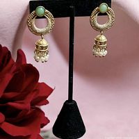 Front view of jade and pearl dangle earrings on stand