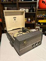 Radio phonograph closed with lid open showing turntable and front speaker