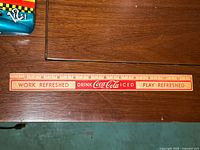Front of Coca-Cola wooden ruler showing slogan and scale