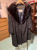 Front view of coat on hanger showing Persian lamb texture and mink collar